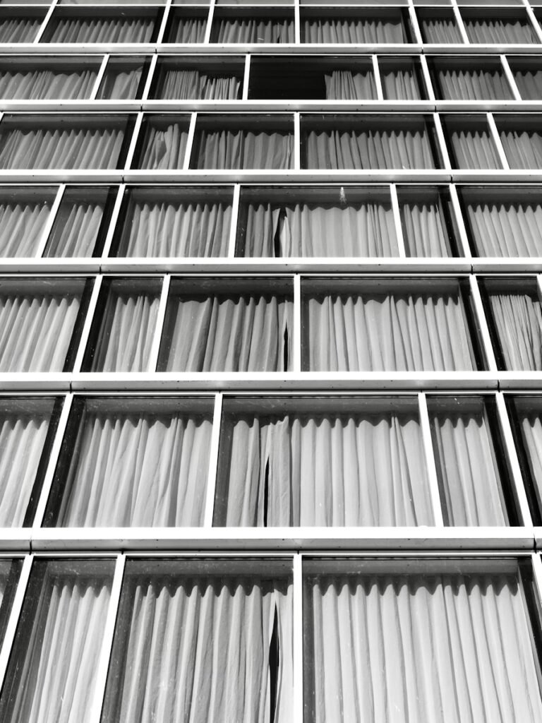 Rows of windows with white curtains in a building.